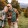 a man and woman standing in a field with trees and grass